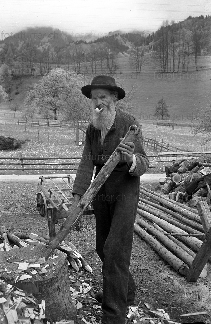 Bauer beim Zuspitzen von Holzpfosten im Berner Oberland, historisches Archiv von Foto Furter